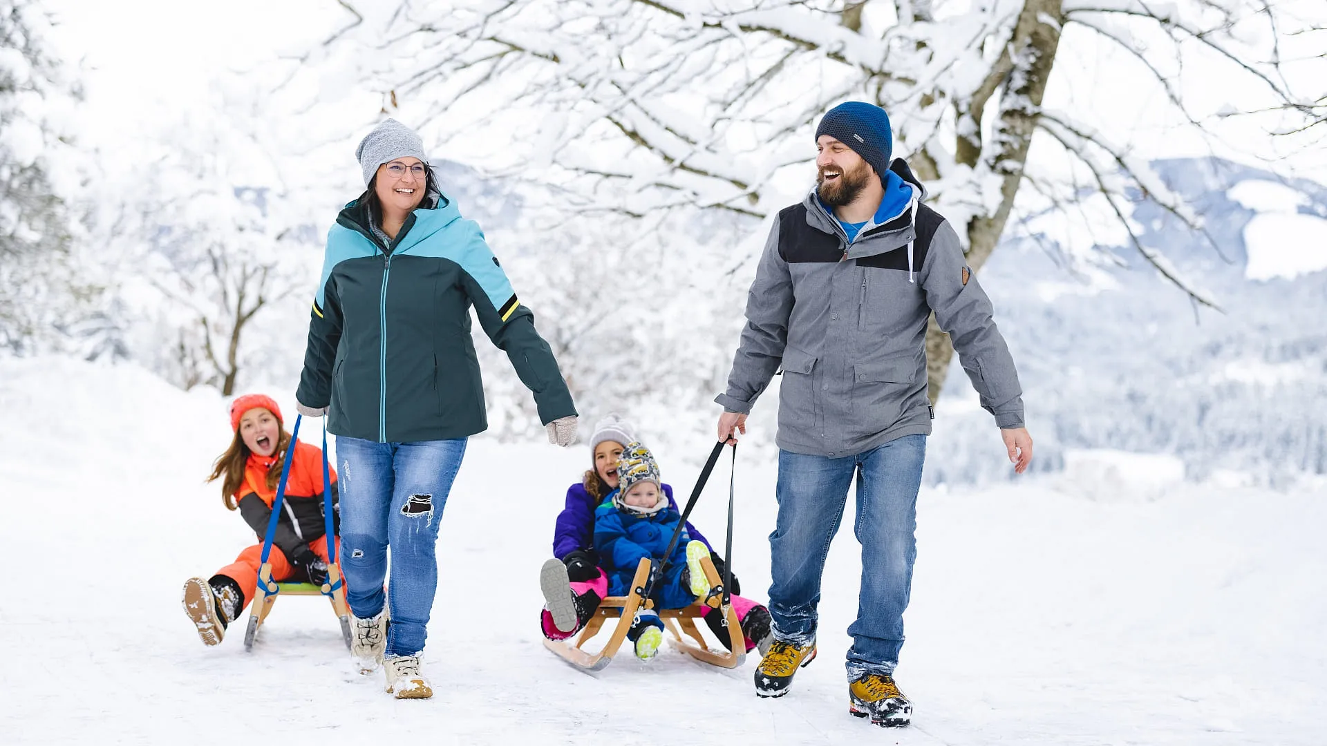Familie mit Schlitten im Schnee spazieren