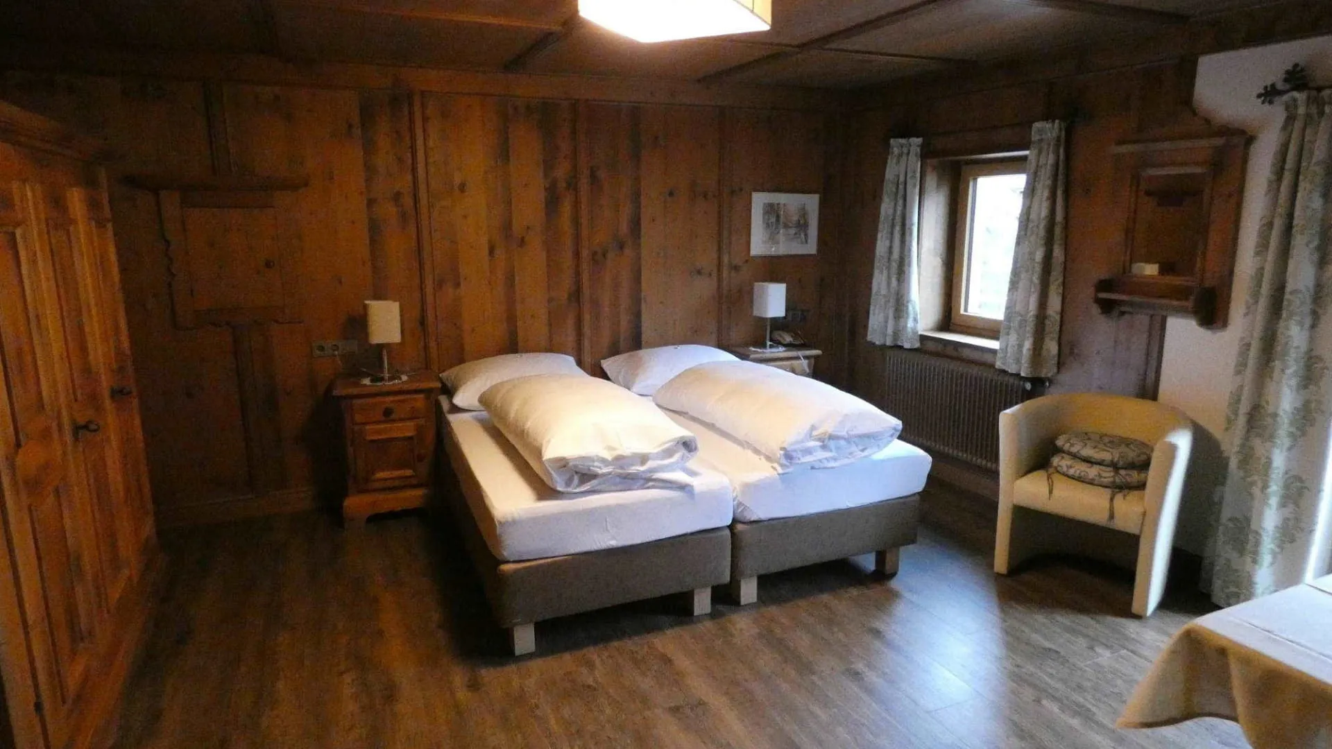 Gemütliches Zimmer mit Holzwänden und zwei Betten.