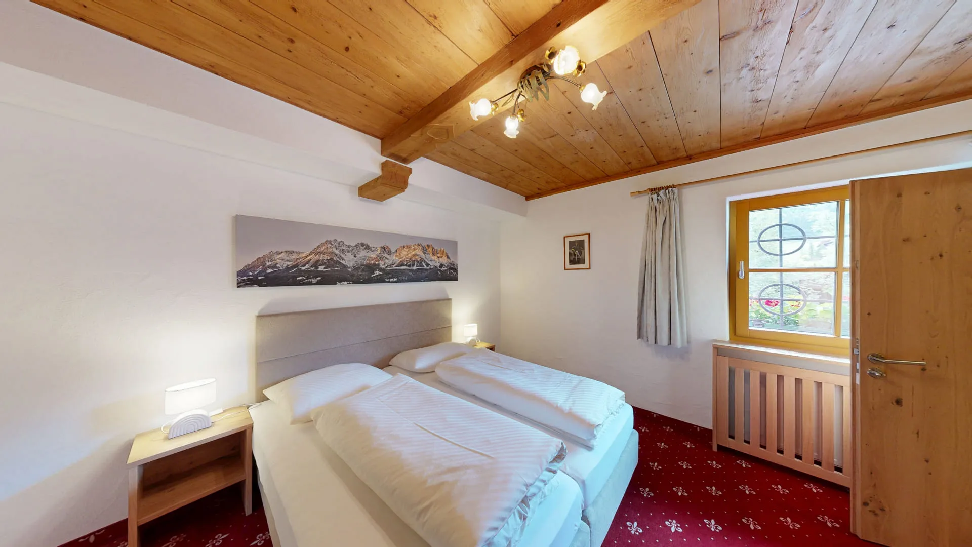 Helles Zimmer mit zwei Betten und Holzdecke.